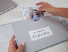 hands placing baby keepsakes in pocket in memory book